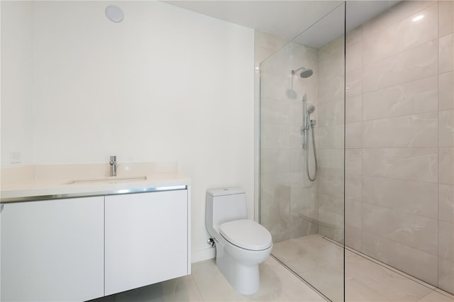 bathroom with tile patterned floors, vanity, toilet, and a tile shower