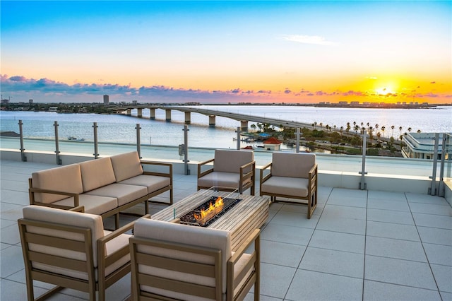 patio terrace at dusk with a water view and an outdoor living space with a fire pit