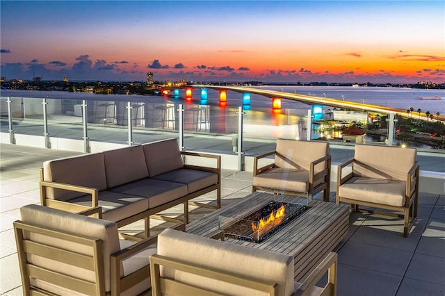 patio terrace at dusk with a water view and an outdoor living space with a fire pit