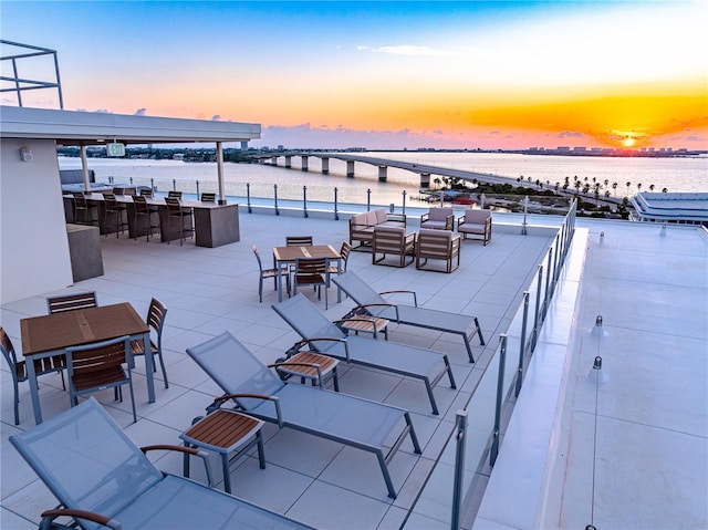 patio terrace at dusk featuring a water view