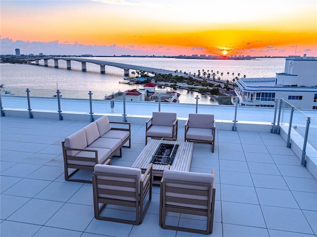 patio terrace at dusk with outdoor lounge area and a water view