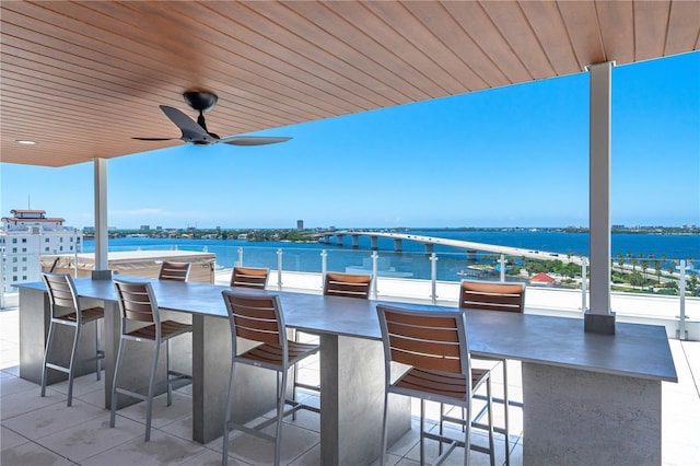 view of patio / terrace featuring ceiling fan, a water view, and exterior bar