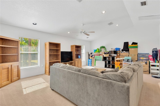 carpeted living room with a textured ceiling, vaulted ceiling, and ceiling fan