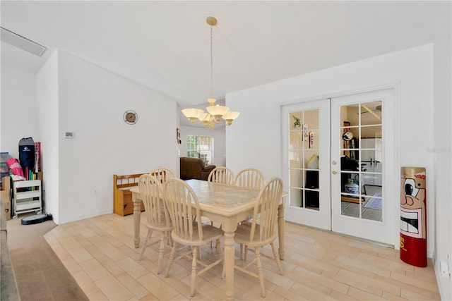 dining area with a notable chandelier, french doors, and light hardwood / wood-style flooring