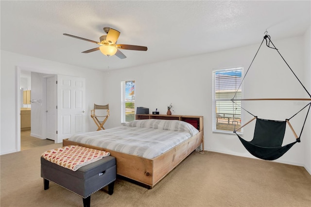 carpeted bedroom featuring a textured ceiling, ensuite bathroom, and ceiling fan