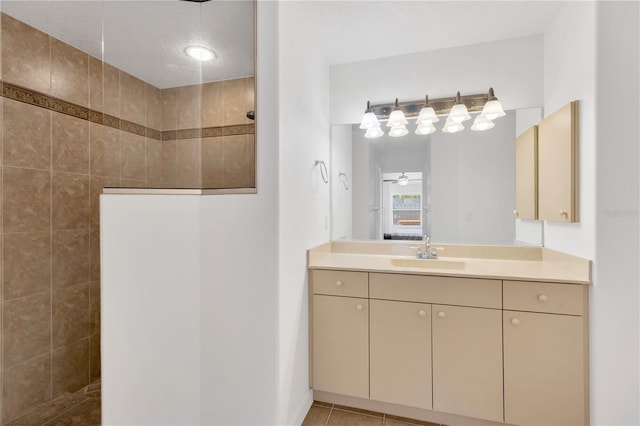 bathroom with a textured ceiling, ceiling fan, walk in shower, and vanity