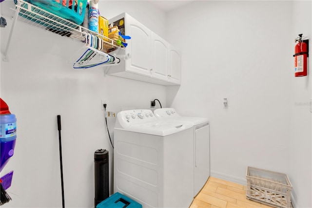 laundry area with cabinets, light wood-type flooring, and separate washer and dryer