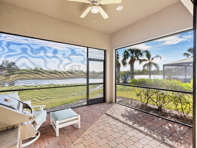 sunroom with ceiling fan, a water view, and plenty of natural light