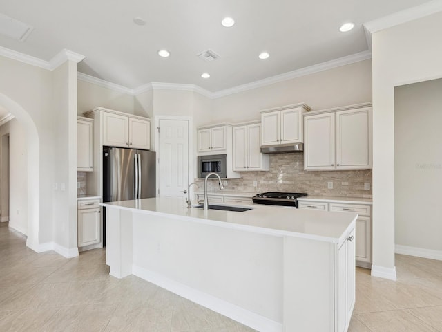 kitchen with tasteful backsplash, stainless steel appliances, sink, light tile patterned floors, and an island with sink