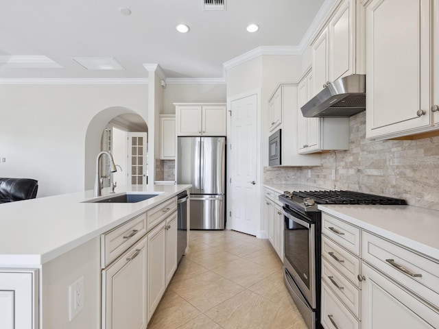 kitchen with crown molding, sink, stainless steel appliances, and a center island with sink