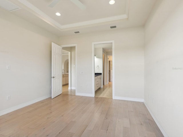 unfurnished bedroom with a raised ceiling, ceiling fan, light hardwood / wood-style flooring, and sink