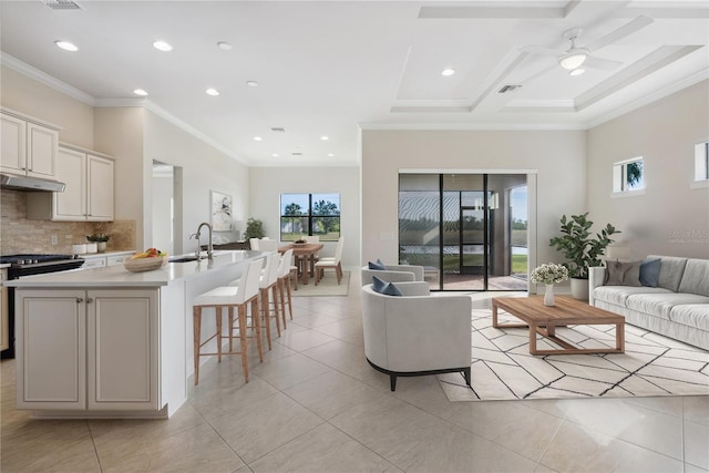 tiled living room featuring ceiling fan, sink, coffered ceiling, and ornamental molding