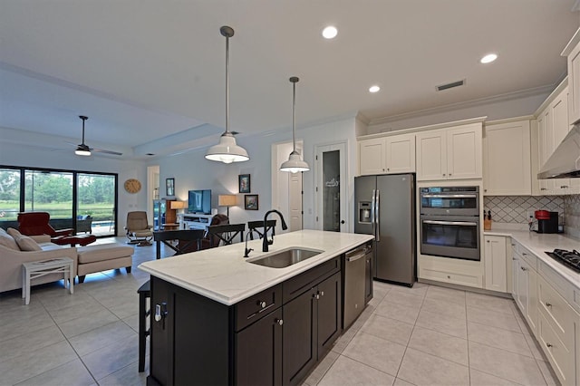 kitchen with sink, hanging light fixtures, appliances with stainless steel finishes, an island with sink, and white cabinets