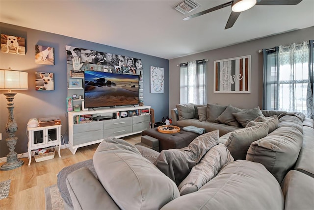 living room featuring light wood-type flooring, ceiling fan, and a healthy amount of sunlight