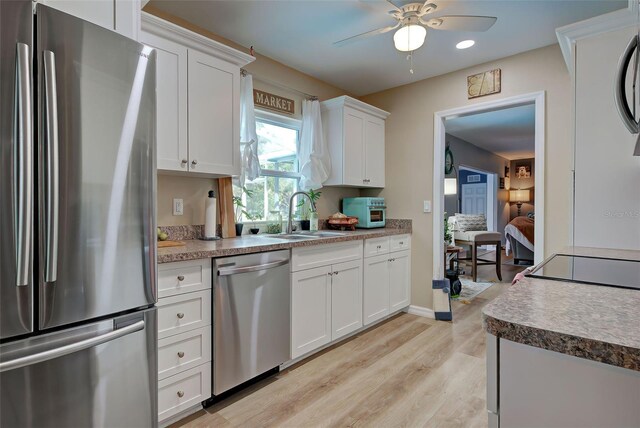 kitchen featuring white cabinets, sink, ceiling fan, light wood-type flooring, and stainless steel appliances