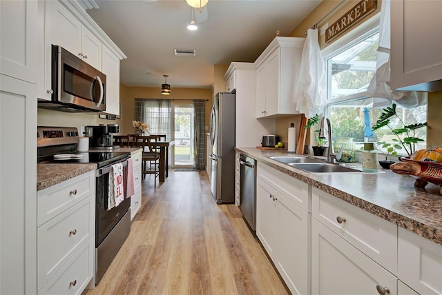 kitchen featuring stainless steel appliances, white cabinetry, light hardwood / wood-style floors, and sink