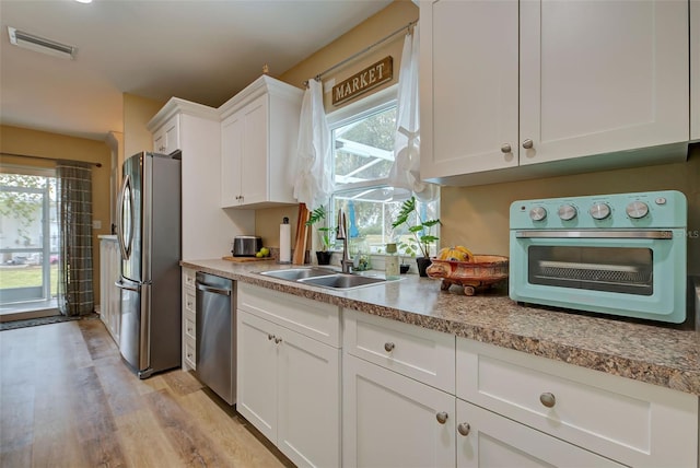 kitchen featuring sink, white cabinets, light hardwood / wood-style flooring, and appliances with stainless steel finishes