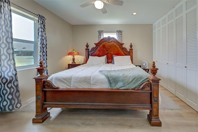 bedroom featuring ceiling fan, a closet, light hardwood / wood-style floors, and multiple windows