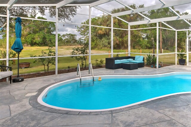 view of swimming pool with an outdoor living space, a patio, a lanai, and a lawn