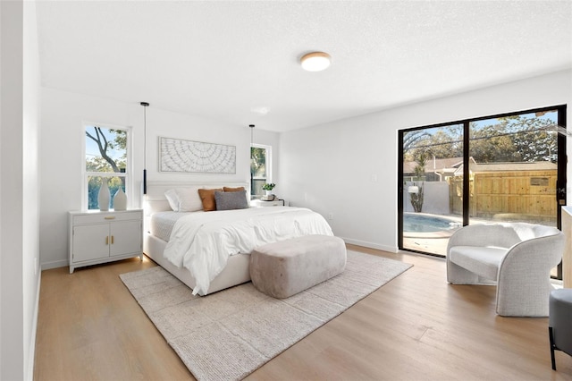 bedroom featuring access to outside, light hardwood / wood-style floors, and a textured ceiling