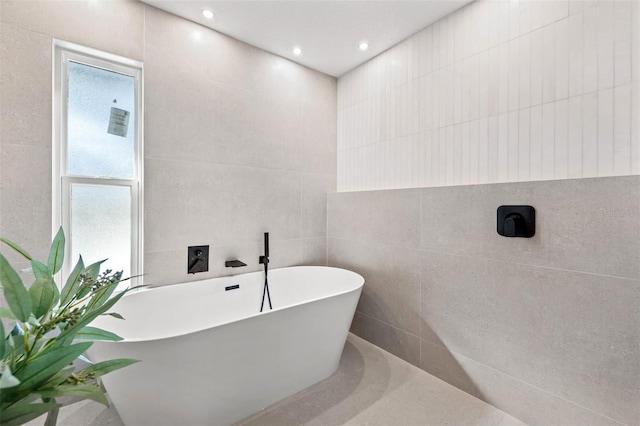 bathroom featuring a washtub and tile walls