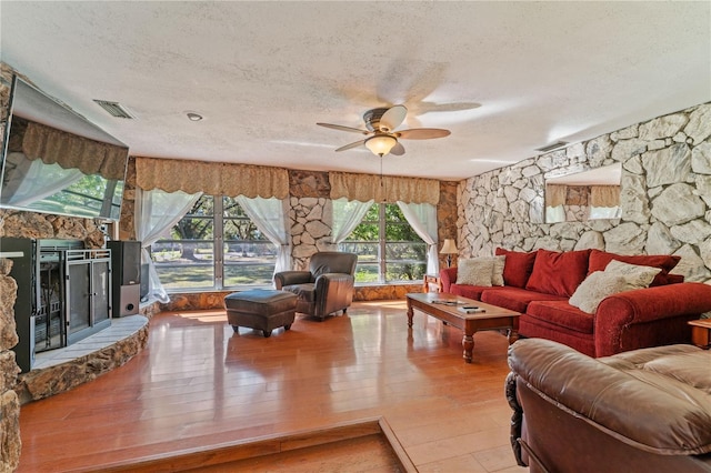 living room featuring wood-type flooring, a textured ceiling, and ceiling fan