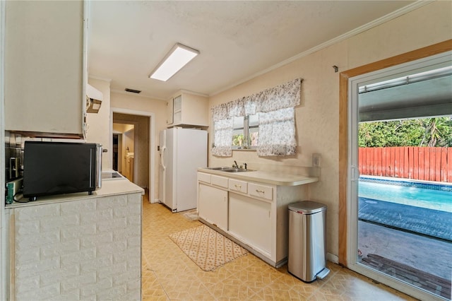 kitchen featuring white cabinetry, sink, white refrigerator with ice dispenser, and ornamental molding