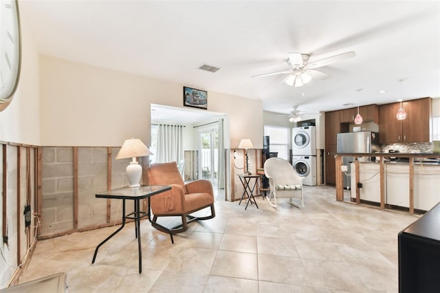 sitting room featuring ceiling fan, light tile patterned floors, and stacked washing maching and dryer