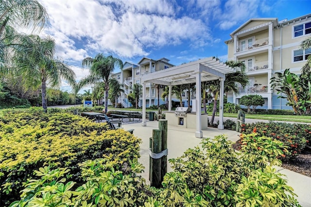 surrounding community featuring a pergola and an outdoor kitchen