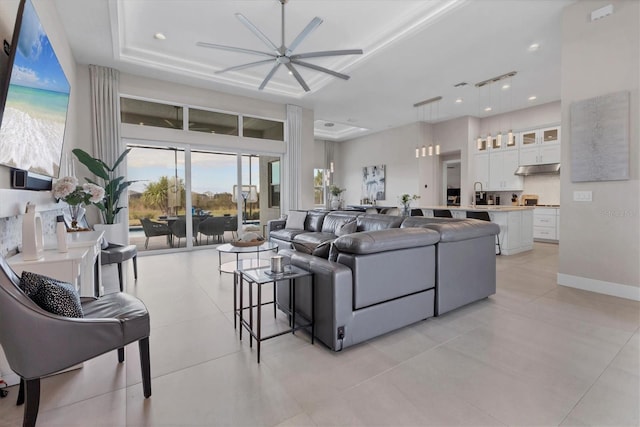 living room with ceiling fan, a raised ceiling, and sink