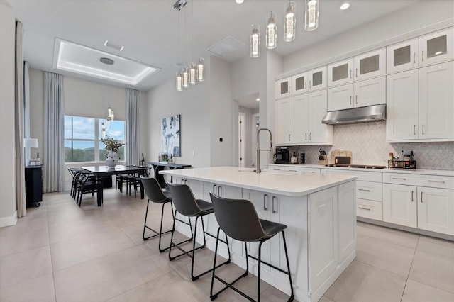 kitchen with tasteful backsplash, sink, pendant lighting, a center island with sink, and white cabinets