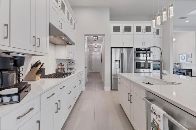 kitchen featuring appliances with stainless steel finishes, tasteful backsplash, white cabinetry, hanging light fixtures, and light tile patterned flooring