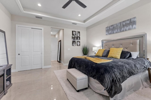 bedroom with ceiling fan, a raised ceiling, and a closet