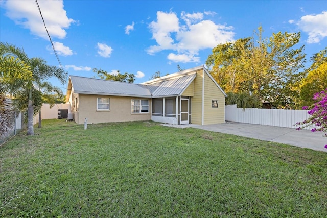 rear view of property featuring a patio area, a sunroom, and a yard