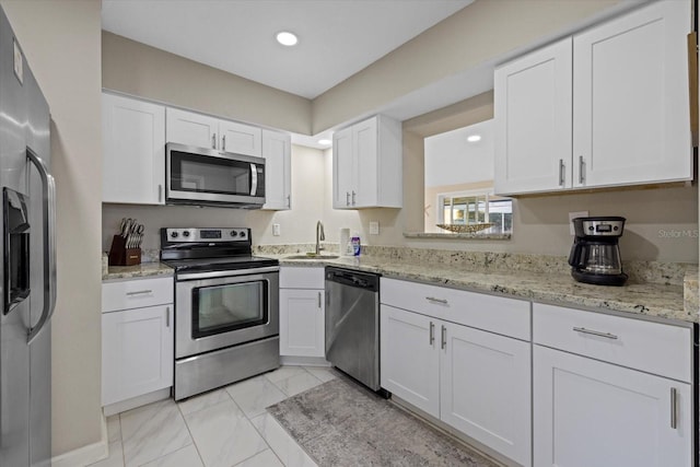 kitchen featuring light stone countertops, stainless steel appliances, white cabinetry, and sink