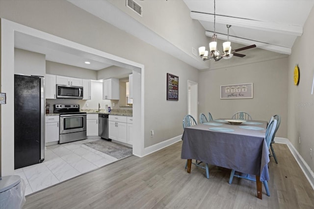 dining room with lofted ceiling with beams, sink, a chandelier, and light wood-type flooring