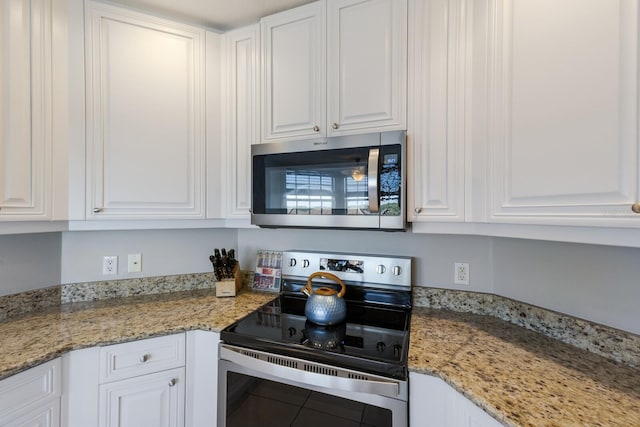 kitchen with white cabinets, stainless steel appliances, and light stone counters