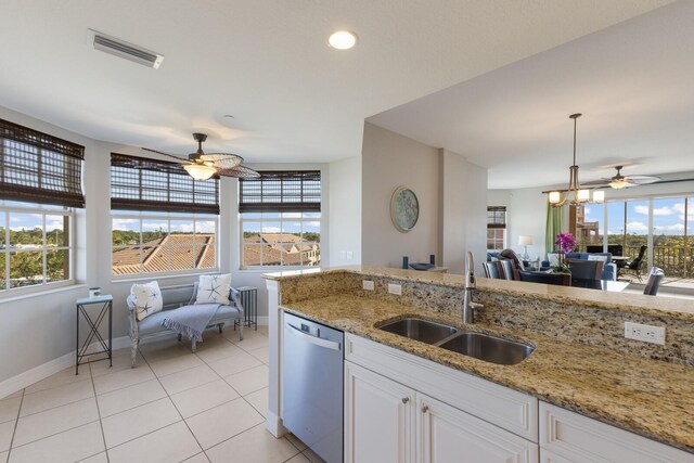 kitchen featuring sink, light tile patterned floors, stainless steel dishwasher, pendant lighting, and white cabinets