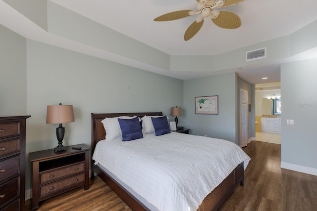 bedroom with dark hardwood / wood-style floors, ceiling fan, and ensuite bath