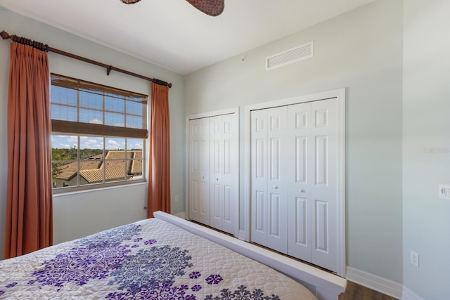 bedroom with ceiling fan, wood-type flooring, and two closets