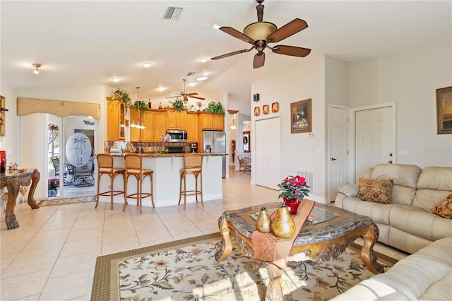 living room featuring ceiling fan, light tile patterned floors, and vaulted ceiling