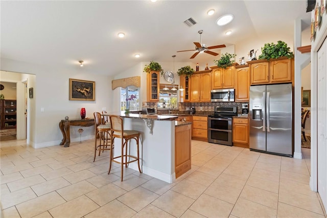 kitchen featuring light tile patterned flooring, lofted ceiling, stainless steel appliances, and a breakfast bar area