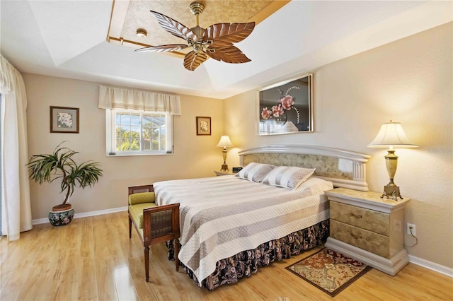 bedroom featuring a raised ceiling, ceiling fan, and hardwood / wood-style flooring