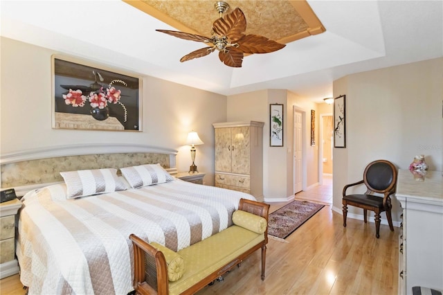 bedroom featuring a tray ceiling, ceiling fan, and light hardwood / wood-style floors