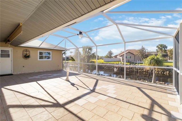 view of patio featuring glass enclosure and a water view