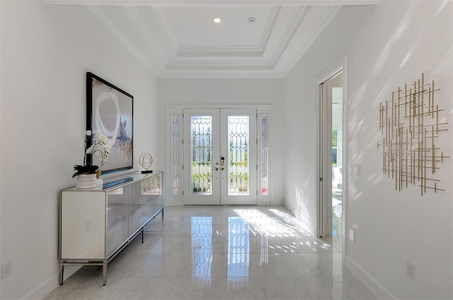 entryway with ornamental molding, a tray ceiling, and french doors