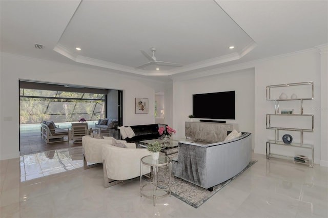 living room featuring a tray ceiling, ceiling fan, and ornamental molding