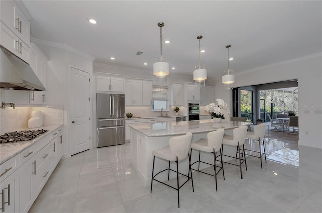 kitchen featuring appliances with stainless steel finishes, tasteful backsplash, white cabinets, a kitchen island, and hanging light fixtures