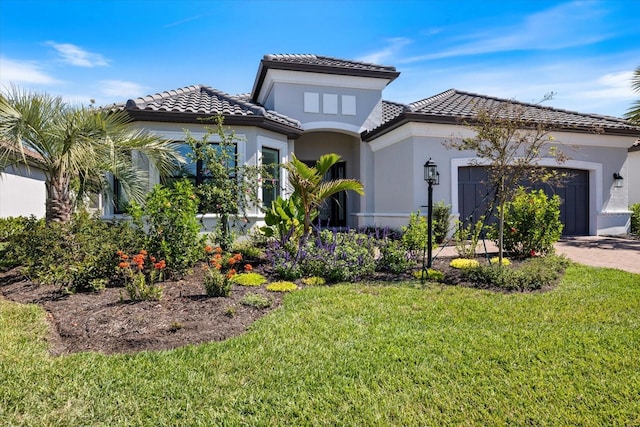 mediterranean / spanish home featuring stucco siding, driveway, a front lawn, an attached garage, and a tiled roof