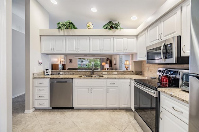 kitchen featuring white cabinets, sink, light tile patterned floors, light stone counters, and stainless steel appliances